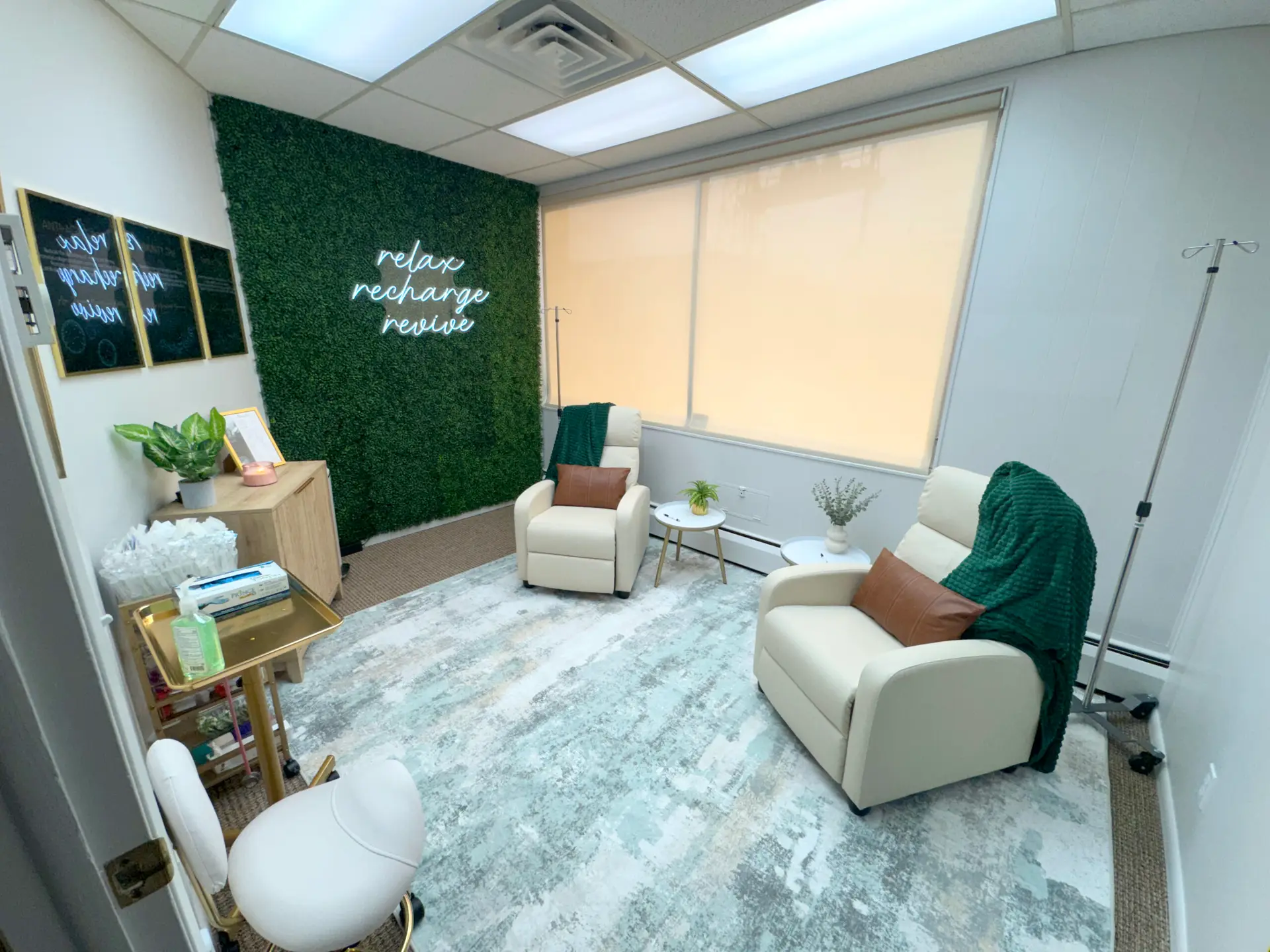vitaledge health and wellness iv therapy room with reclining chairs green accent wall neon relax recharge revive sign and cozy blankets